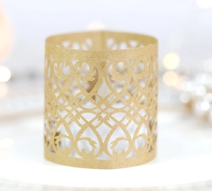 Macro view of gold laser-cut paper tea light wrap with elegant scroll patterns