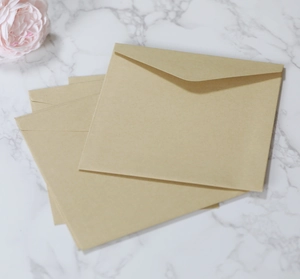 Close-up of square kraft paper envelopes with V-flap on white marble background