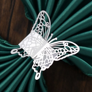 Macro shot of laser-cut white butterfly paper napkin ring on dark green satin fabric