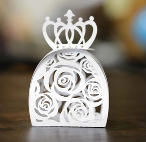 Close-up of white paper candy box featuring crown top and laser-cut rose patterns