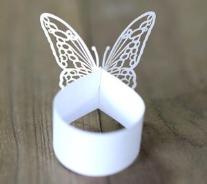 Detailed laser-cut white butterfly napkin ring with intricate floral cutout patterns