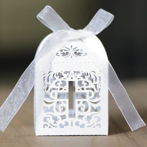 Detail of white laser-cut wedding candy box featuring an elegant cross and white organza ribbon