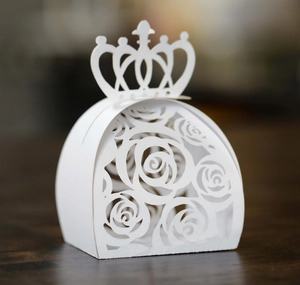 Detailed macro view of laser-cut rose patterns on crown-shaped white favor boxes