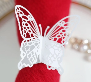 Detailed view of 3D laser-cut white butterfly napkin ring on a red elegant fabric