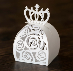 Macro shot of white crown-shaped wedding gift box with rose hollow patterns