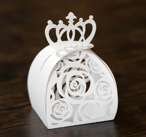 Detail of white laser-cut rose hollow candy box with crown-shaped top on wood surface