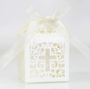 Detail of white laser-cut wedding favor box featuring an elegant hollow cross design