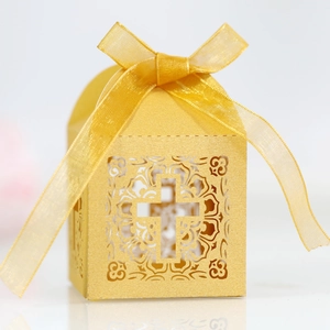 Golden laser-cut wedding favor box with hollow cross design and decorative ribbon bow
