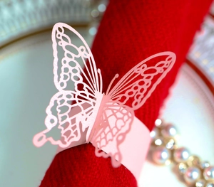 Macro shot of laser-cut pink butterfly napkin ring with intricate wing details for weddings