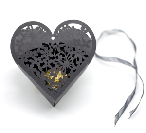 Macro detail of black heart-shaped gift box with laser-cut butterfly floral patterns