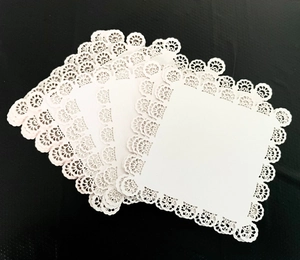 Detailed view of white square hollow lace paper with intricate laser-cut floral patterns