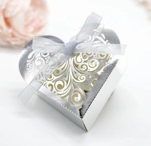 Detail of silver heart shaped candy box with hollow floral pattern and silk ribbon