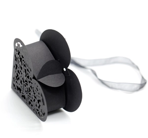 Close-up of laser-cut heart pattern on black paper wedding candy box with ribbon