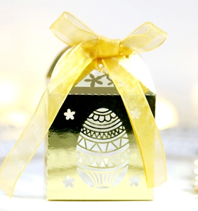 Vue détaillée d'une boîte à bonbons dorée de Pâques avec un ruban en organza jaune