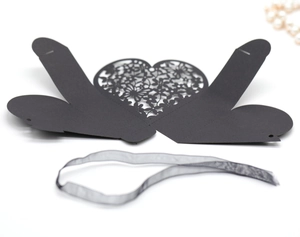 Flat lay of laser-cut black hollow heart gift box with elegant matching silk ribbon