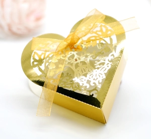 Detailed laser-cut floral pattern on golden heart-shaped favor box with ribbon