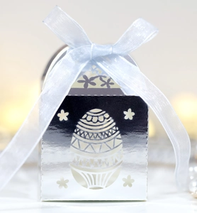 Détail boîte à bonbons Pâques argentée avec motifs découpés et ruban en organza bleu