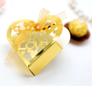 Macro shot of gold laser-cut heart favor box with In Love text and gold ribbon bow