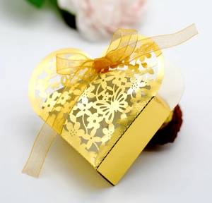 Close-up of golden hollow heart candy box with laser-cut floral patterns and ribbon