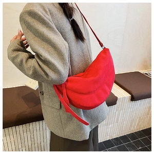 Detailansicht einer hellroten Halbmond-Tasche aus Wildleder am Model getragen