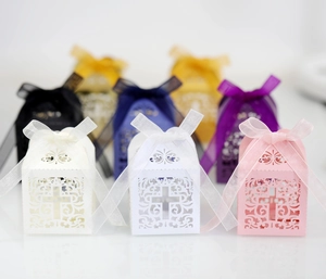 Detailed laser-cut hollow cross candy boxes with matching organza ribbons and swirls