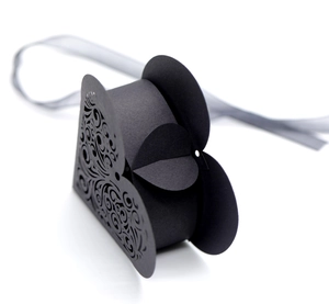 Detailed macro view of laser-cut swirl patterns on a black triangular paper gift box