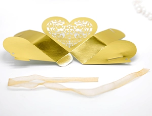 Flat lay of gold laser-cut heart candy box template with elegant champagne ribbon