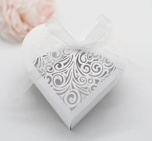 Detail of white heart-shaped wedding favor box with laser-cut lace and organza ribbon