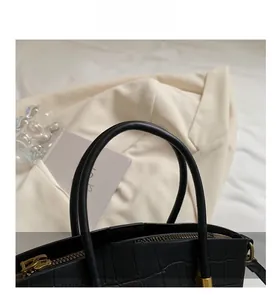 Detail of black crocodile embossed leather bucket bag with round handle and gold hardware