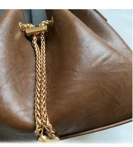 Close-up of brown grain leather bucket bag with gold metal chain drawstring detail