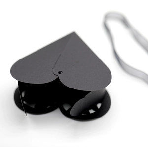 Macro detail of a black matte heart-shaped gift box with intricate laser-cut hollow patterns