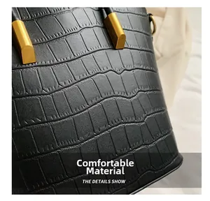 Close-up of black crocodile-embossed leather texture with golden D-ring metal hardware