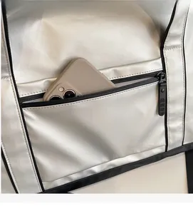 Détail du sac de sport argenté montrant la poche zippée avec un smartphone dedans