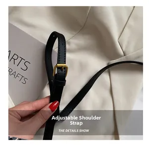 Detail of adjustable black leather shoulder strap with elegant gold metal buckle hardware