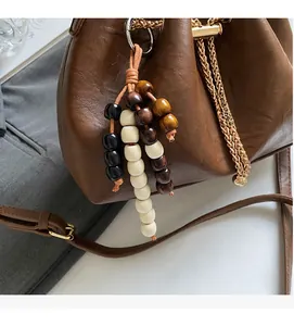 Detail of brown leather bucket bag with wooden bead tassel and metal ring chain