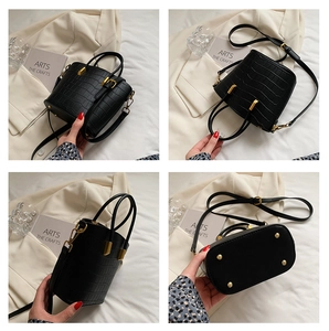Detailed view of black crocodile pattern bucket bag with gold hardware and metal feet