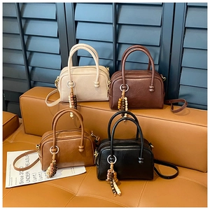 Sacs Boston rétro en ivoire, marron, rouge et noir avec breloques sur tabouret en cuir