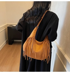 Detailed view of caramel suede hobo bag featuring long bohemian tassels and metal rings