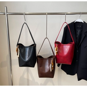 Detailed view of leather bucket bags in black, brown, and red with wooden bead charms