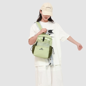 Detail view of water-resistant green crossbody bag with mesh pocket and zipper layers