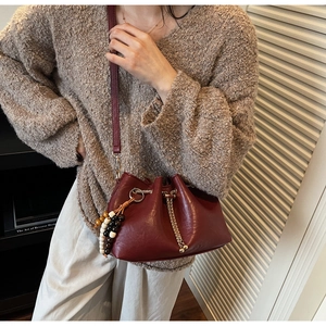 Chic burgundy drawstring bucket bag with gold chain and colorful beaded tassel detail