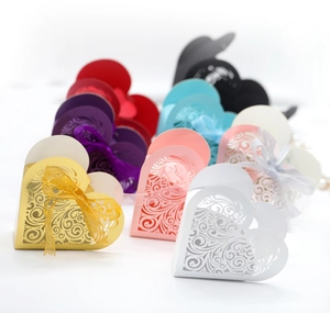 Close-up of laser-cut heart favor boxes with intricate vine patterns and silk ribbons