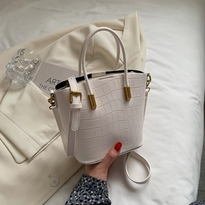 Close-up of white crocodile pattern bucket bag featuring gold hardware and PU leather texture