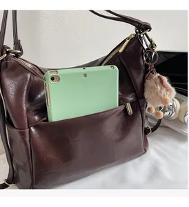 Detail of dark brown vintage faux leather backpack showing spacious front pocket capacity