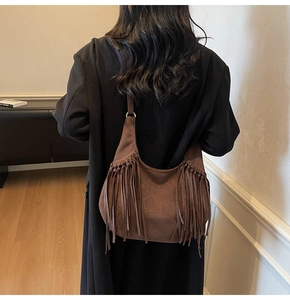 Détail du sac hobo en daim marron foncé avec de longues franges et anneaux métalliques