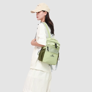 Side view of a large green commuter backpack with multi-pocket storage on a female model