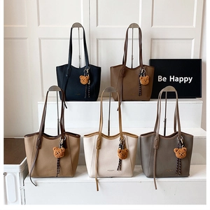Detailed display of five colors of vintage leather tote bags with plush bear pendants