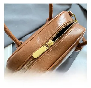 Détail du sac bowling en cuir marron avec fermeture éclair dorée et coutures de qualité