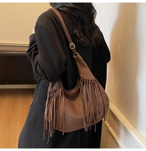 Detail of vintage coffee suede crossbody bag with long tassels and gold metal buckle