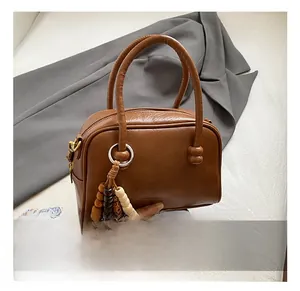 Détail du sac bowling en cuir marron avec breloque en perles de bois et zip élégant